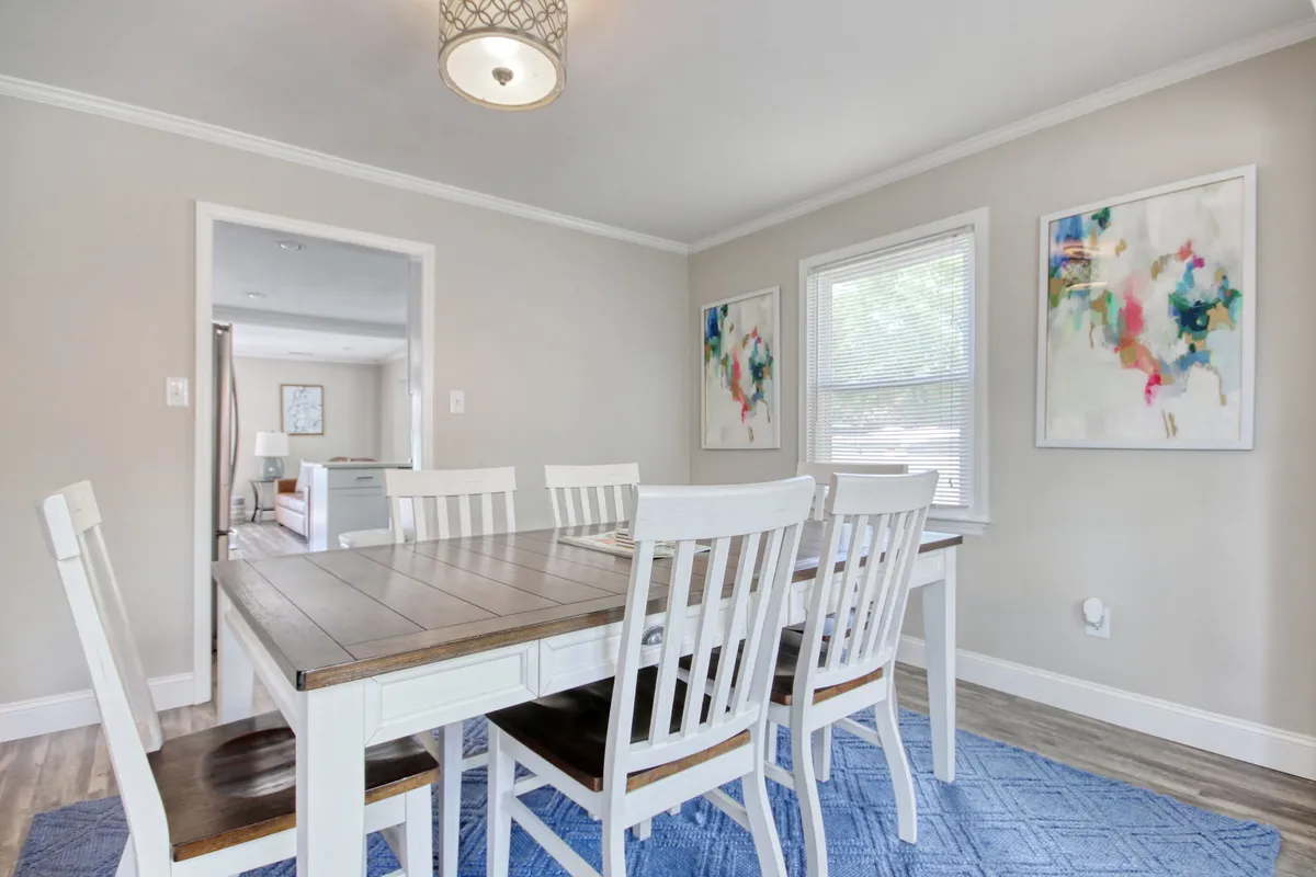 A bright, inviting dining area with a large table under a chandelier, surrounded by artwork. The space is designed for family meals and gatherings, capturing the essence of shared dinners after a fun day out.