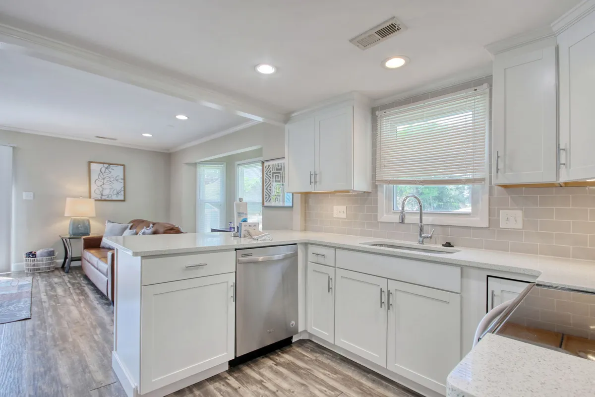 A bright, modern kitchen with white cabinetry, stainless steel appliances, a central island, and abundant natural light streaming in through windows. The space is cozy yet functional, ideal for hosting dinner parties, family gatherings, and meal prepping.