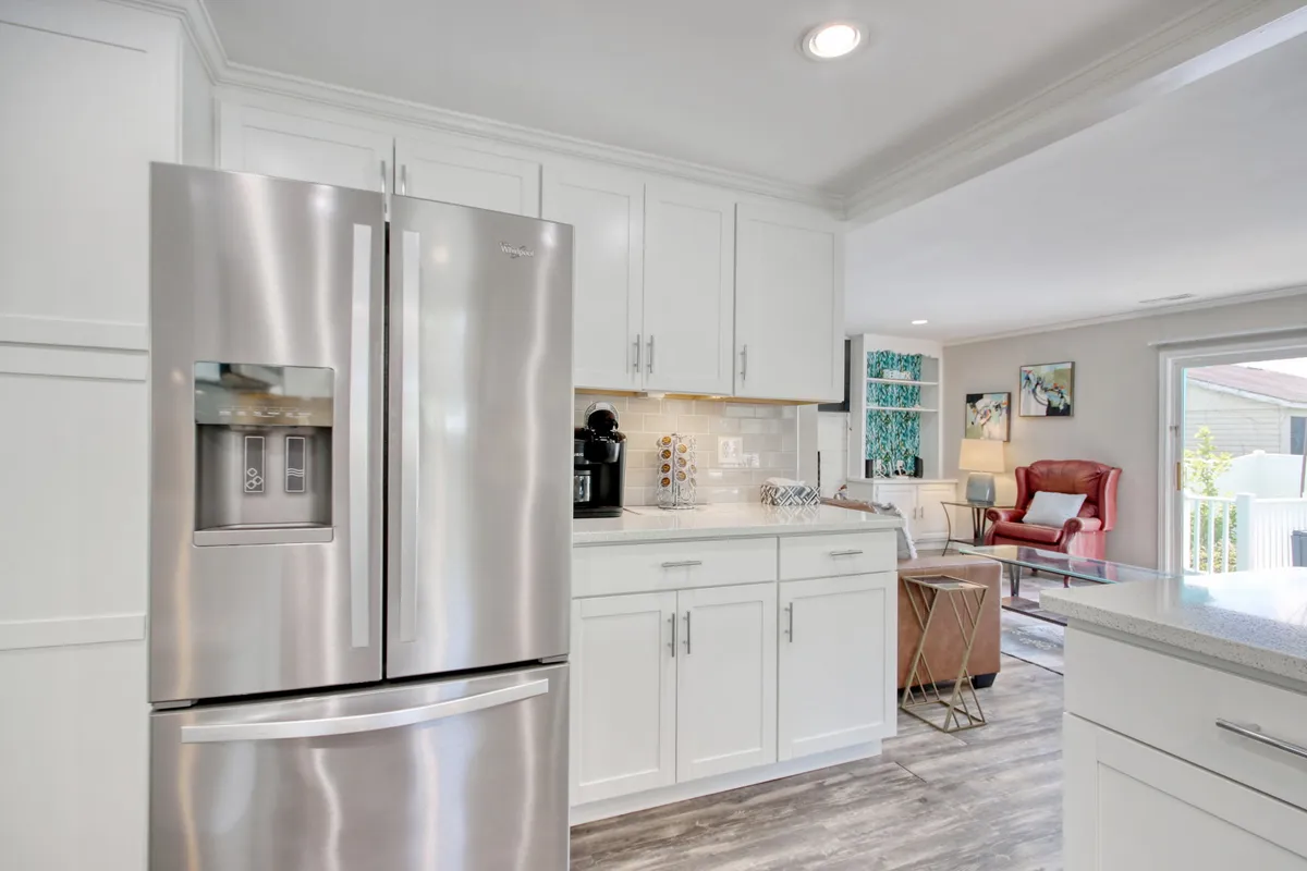 A modern kitchen with stainless steel appliances and white cabinetry, adjacent to a cozy armchair. The space is perfect for preparing meals and relaxing, emphasizing the comforts of home after a day of activities.